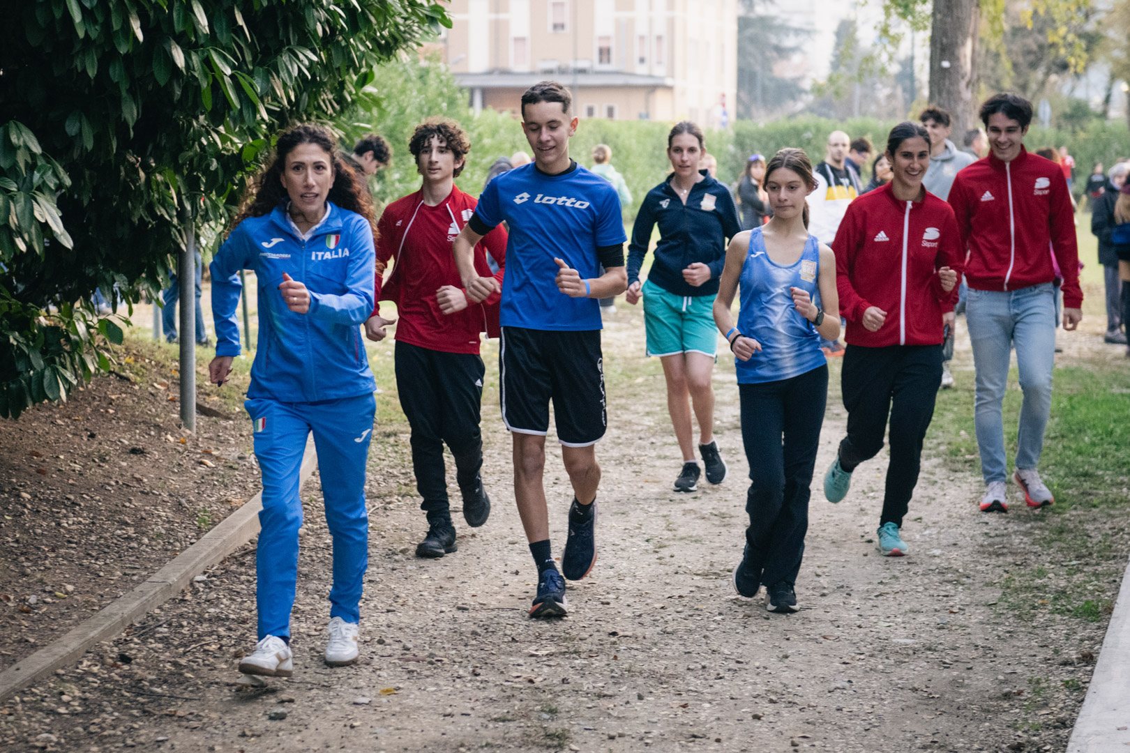 Un'atleta azzurra corre insieme a un gruppo di ragazzi